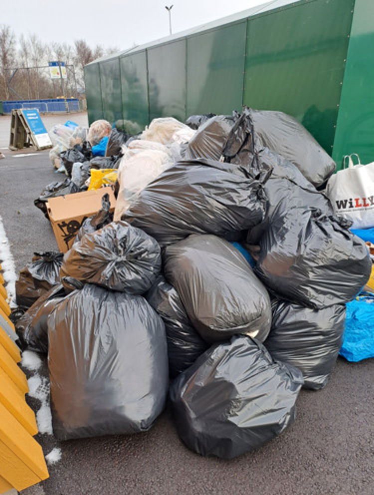 Berg av textilinsamling på återvinningscentral. 